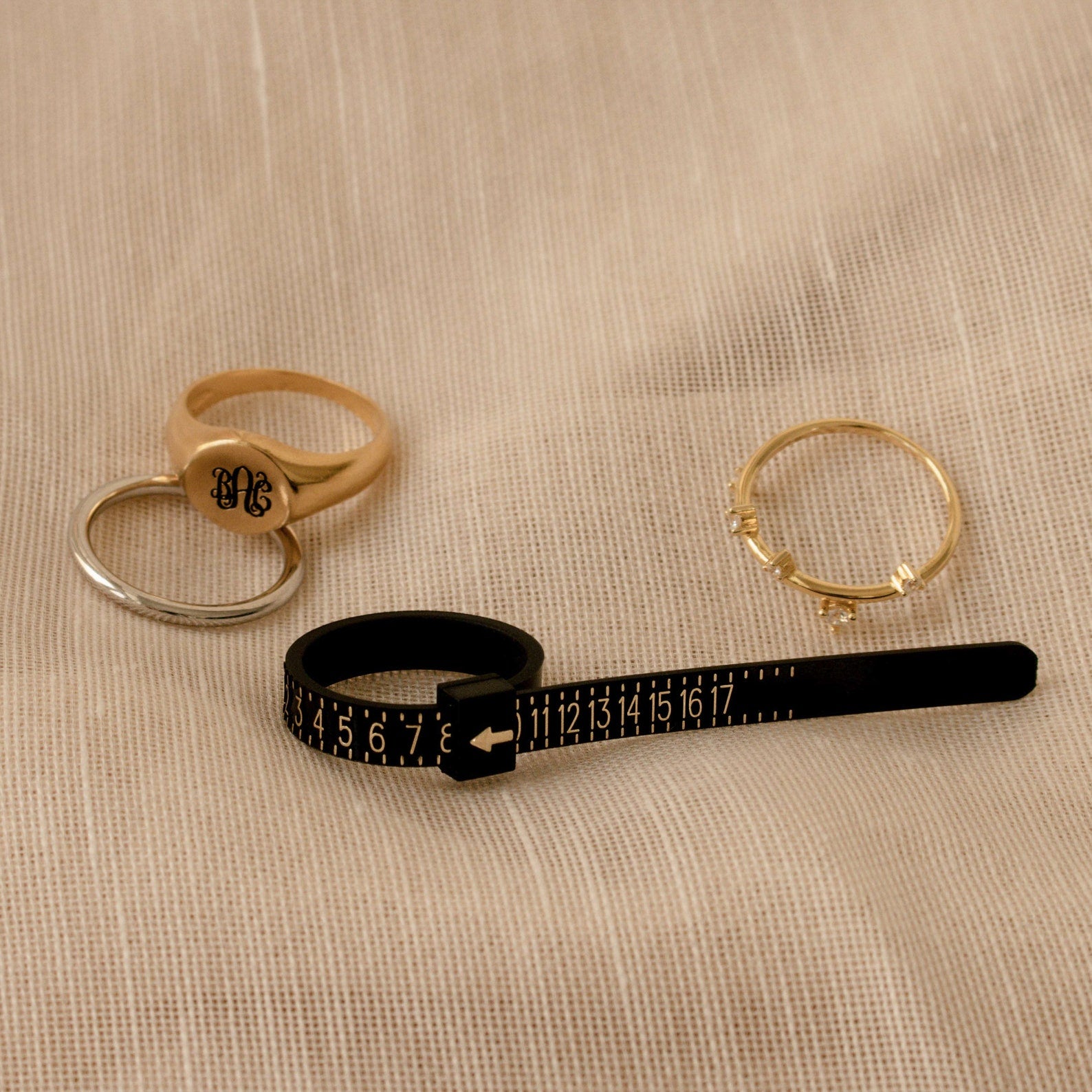 The Ring Sizer is shown on a beige textured fabric, making it easy to achieve accurate sizing for your perfect ring fit.