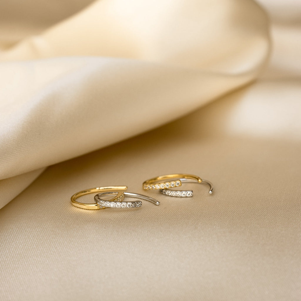 Pave Wire Diamond Hoops in gold and silver, set with sparkling diamonds, are displayed on beige satin fabric—ideal for fans of minimalist diamond earrings.