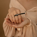 A person wearing two rings, including a small black wrench-shaped one, highlights the need for accurate sizing with the Ring Sizer when choosing unique ring styles.
