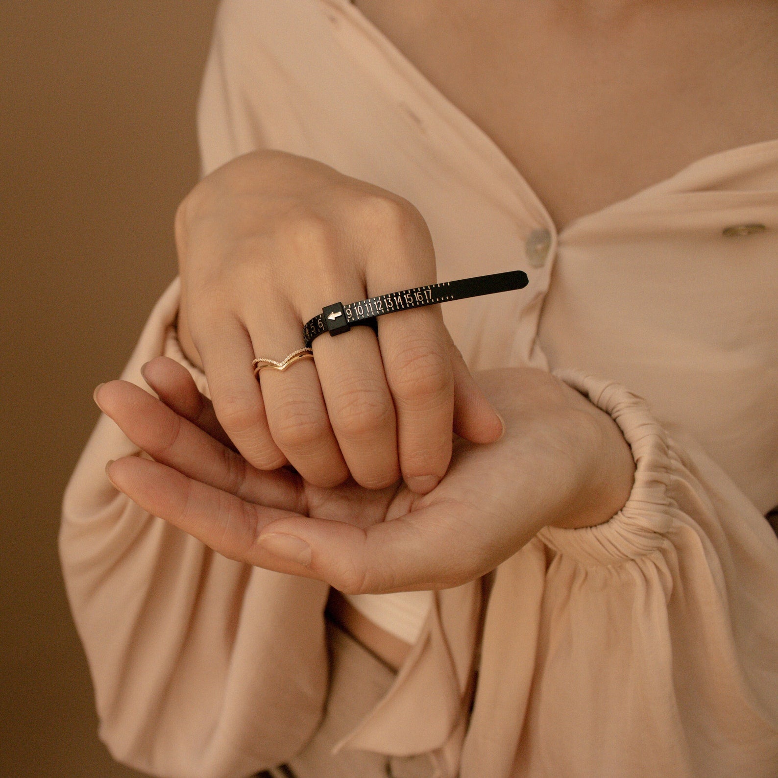 A person wearing two rings, including a small black wrench-shaped one, highlights the need for accurate sizing with the Ring Sizer when choosing unique ring styles.