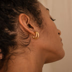 Close-up of a woman's ear wearing Jenna Triple Hoops, thick gold earrings with curls framing her minimalist style.