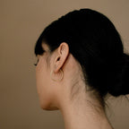 A woman with dark hair in a bun models the Medium Thin Hoops against a plain tan background.