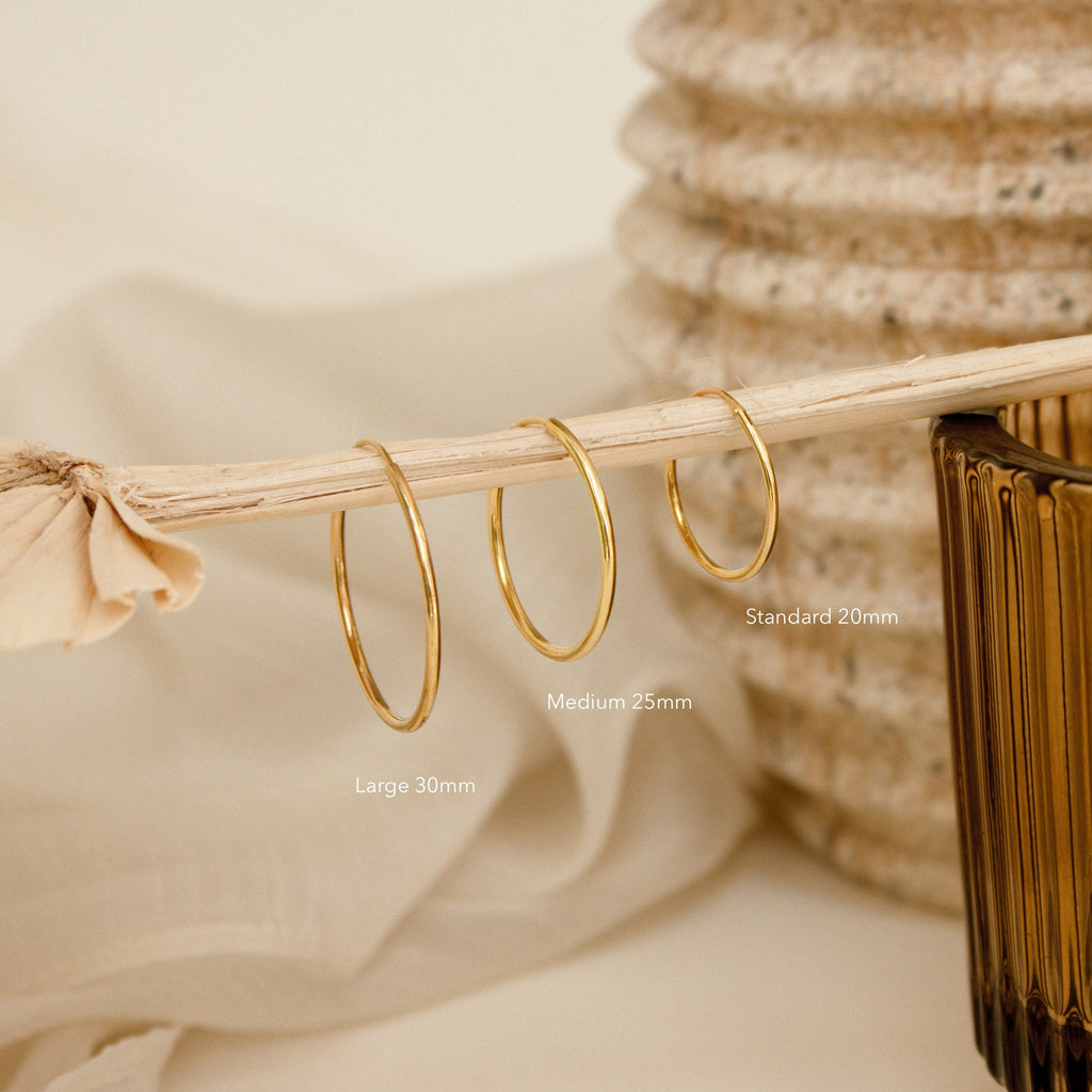 The Large Thin Hoops—sleek, lightweight earrings—add simple elegance to your daily style. Shown here with matching medium and small sizes on a dried stem, they pair perfectly with any outfit.