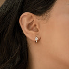 Close-up of a woman's ear wearing Scarlett Pearl Huggies, showcasing a silver hoop adorned with a heart-shaped charm.
