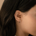 Close-up of a woman’s ear wearing Small Thin Hoops—simple earrings ideal for everyday wear—with dark hair draped behind her ear.