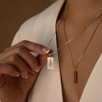 A woman in a white blouse holds the Tarot Necklace in Box Chain—its silver pendant layered above a gold chain, her style suggesting secrets inspired by the Major Arcana.