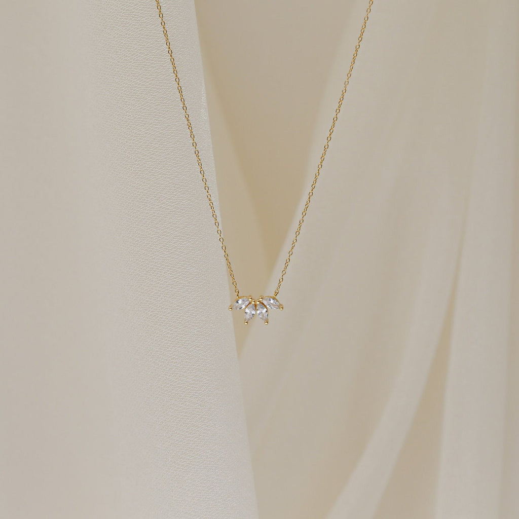 A delicate gold chain necklace featuring a small cluster of marquise-cut clear stones arranged like petals.