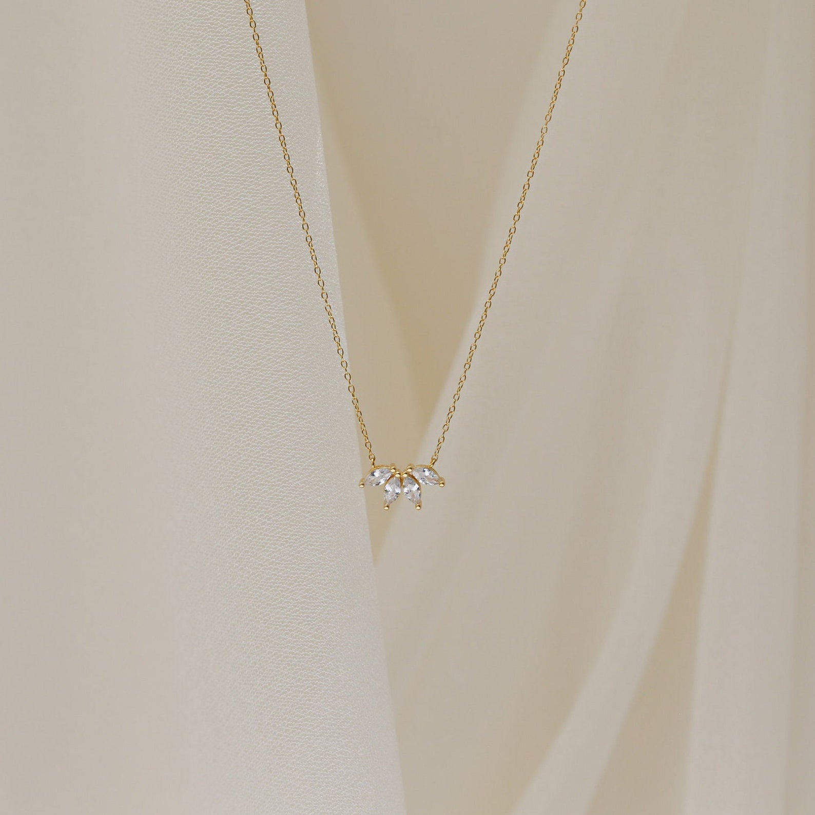 A delicate gold chain necklace featuring a small cluster of marquise-cut clear stones arranged like petals.