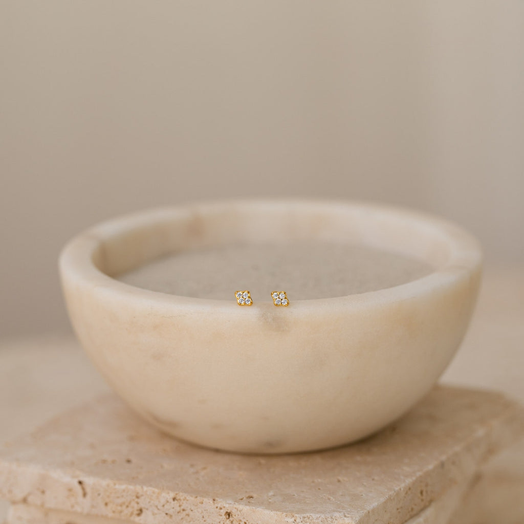 Avery Geometric Diamond Studs are displayed in a bowl of water, accentuating their modern pavé setting and stylish design.