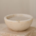 Avery Geometric Diamond Studs are displayed in a bowl of water, accentuating their modern pavé setting and stylish design.