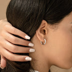 A woman with long dark hair displays nude manicured nails and the Madison Hoops for a chic, minimalist look.