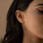 Close-up of a woman's ear wearing Avery Geometric Diamond Studs, paired with winged eyeliner makeup.