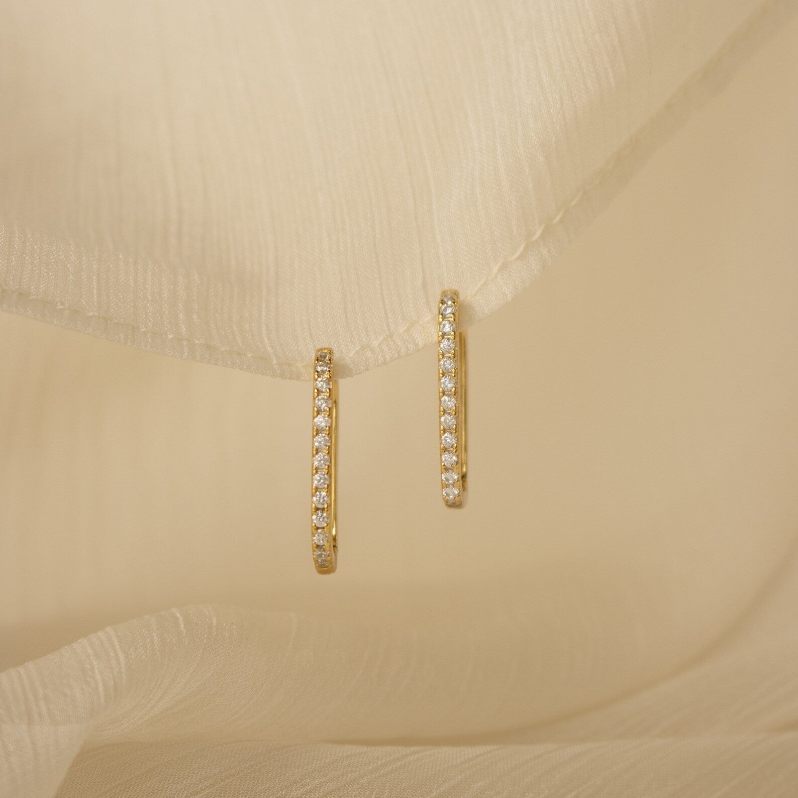 Pave Link Earrings with sparkling diamonds featured on soft, cream-colored fabric.