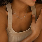 Woman wearing a beige knit tank top and the Hana Diamond Station Necklace, a delicate silver layering piece adorned with small triangle pendants.
