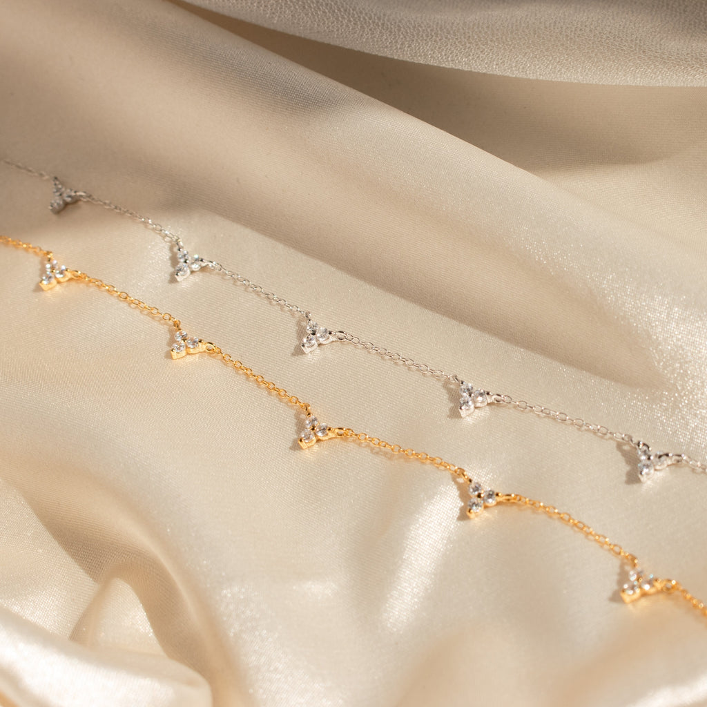The Hana Diamond Station Necklace, delicately crafted, is displayed on soft, shimmering beige fabric.