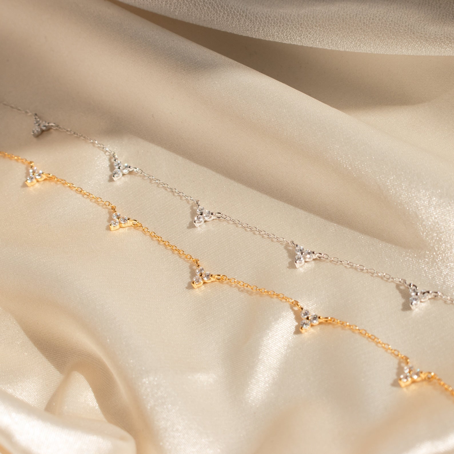 The Hana Diamond Station Necklace, delicately crafted, is displayed on soft, shimmering beige fabric.