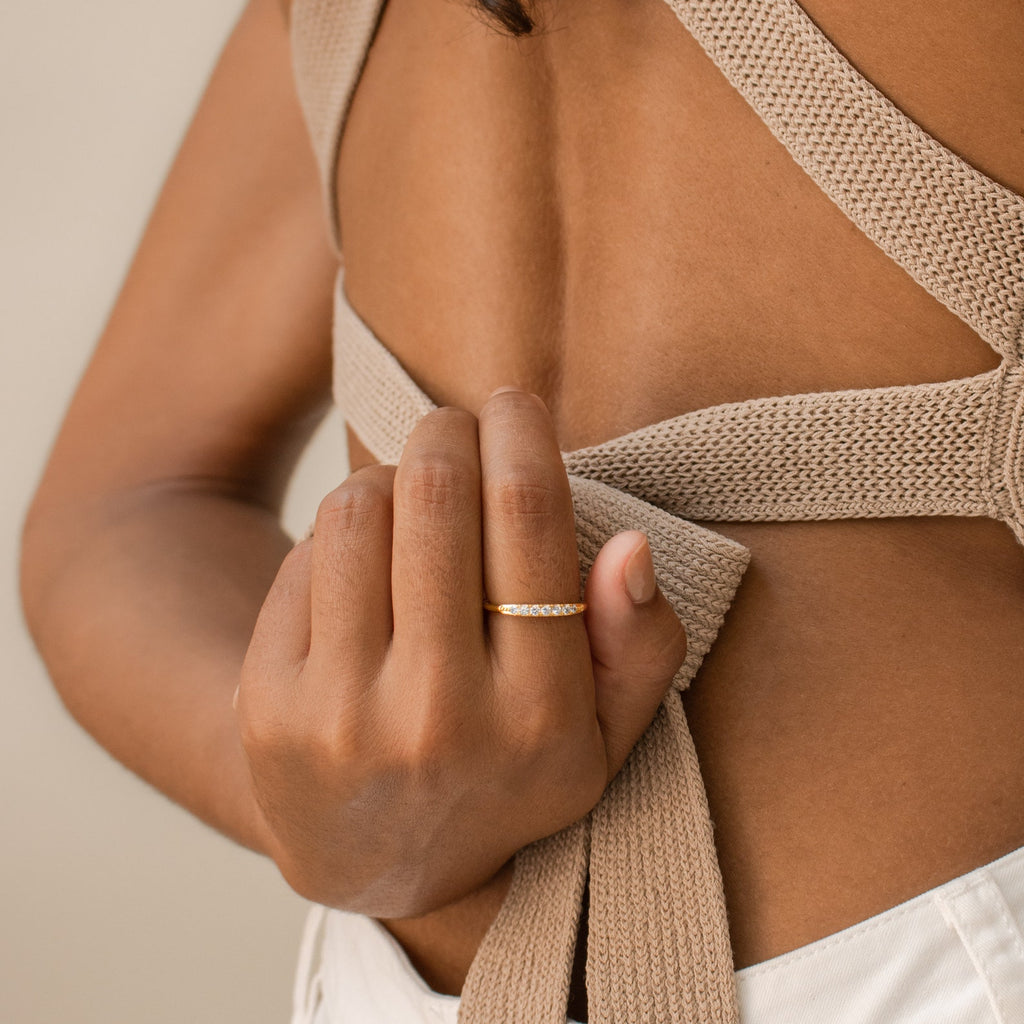 A hand wearing the Lace Pave Ring holds a beige knitted strap on an open-back top.