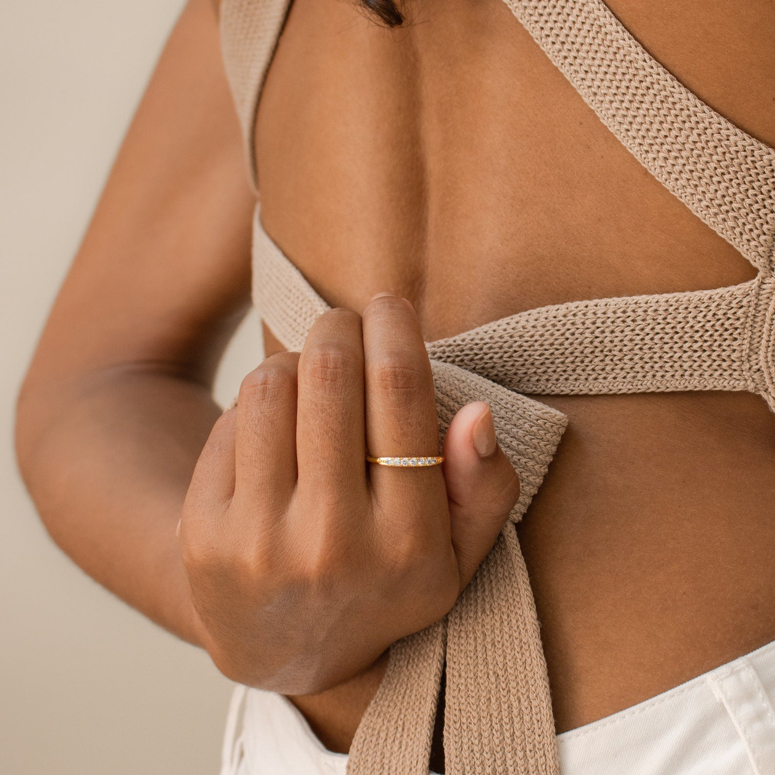 A hand wearing the Lace Pave Ring holds a beige knitted strap on an open-back top.