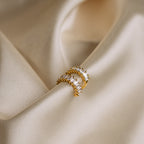Two Baguette Ear Cuffs with clear gemstones rest on soft, light beige fabric, capturing a diamond-like sparkle.