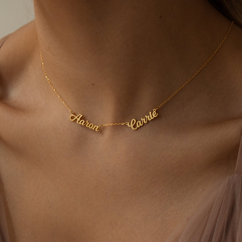 The Mellow Multiple Name Necklace in gold, shown with "Aaron" and "Carrie," is a meaningful jewelry piece, elegantly worn by women and an ideal personalized gift for mom.
