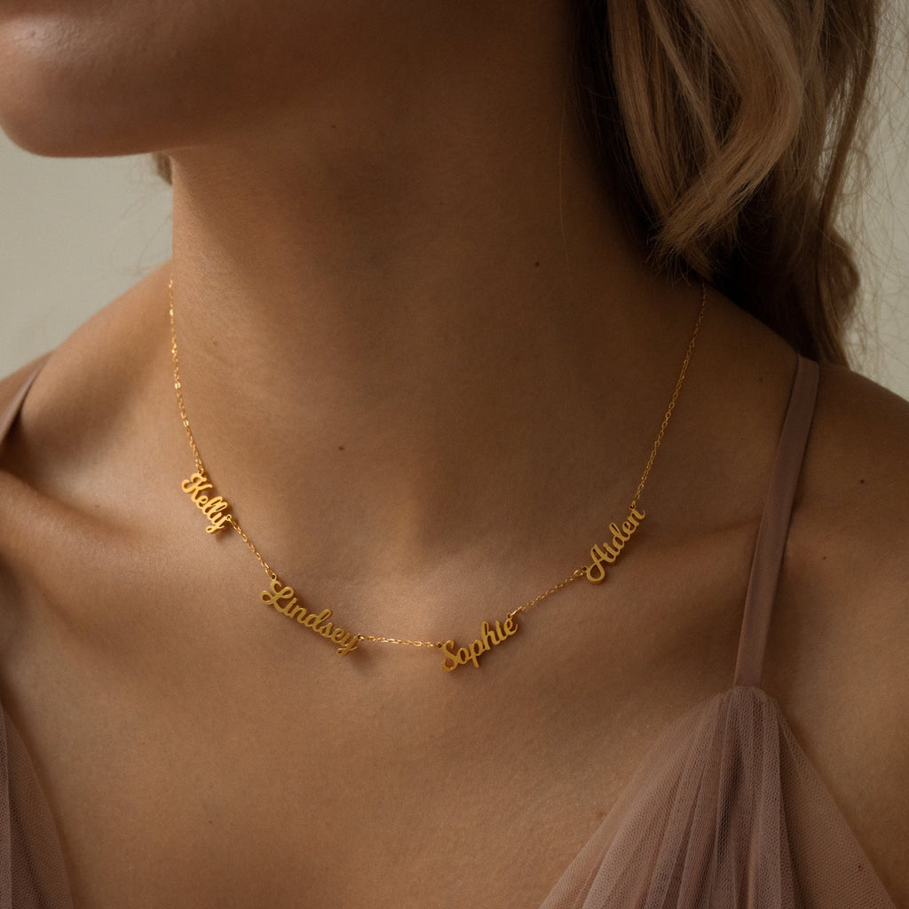 A woman wears the Mellow Multiple Name Necklace, showcasing the names Katy, Lindsey, Sophie, and Adler in elegant cursive—a beautiful piece of jewelry and a thoughtful gift for mom.