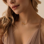 A woman wears the Tiny Summer Name Necklace in a delicate gold font, styled with a sheer nude dress.