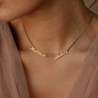 Carrie Multiple Name Necklace in Box Chain, featuring "Matthew" and "Audrey" in cursive, worn with a sheer beige top—an ideal personalized jewelry piece.
