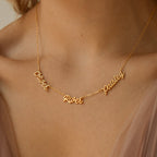 The Paris Multiple Name Necklace in gold, featuring custom cursive names Oliver, River, and Paisley, elegantly adorns a woman's neck.
