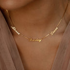 Close-up of a gold Carrie Multiple Name Necklace in Box Chain, featuring the names Alessa, Presley, and Gianni in cursive on a person's neck.