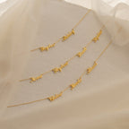 The Carrie Multiple Name Necklace is displayed on textured cream fabric with sheer beige fabric draped above.