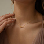 Close-up of a woman wearing the Tiny London Name Necklace, a customizable gold name plate with "Lauren" in elegant cursive lettering.