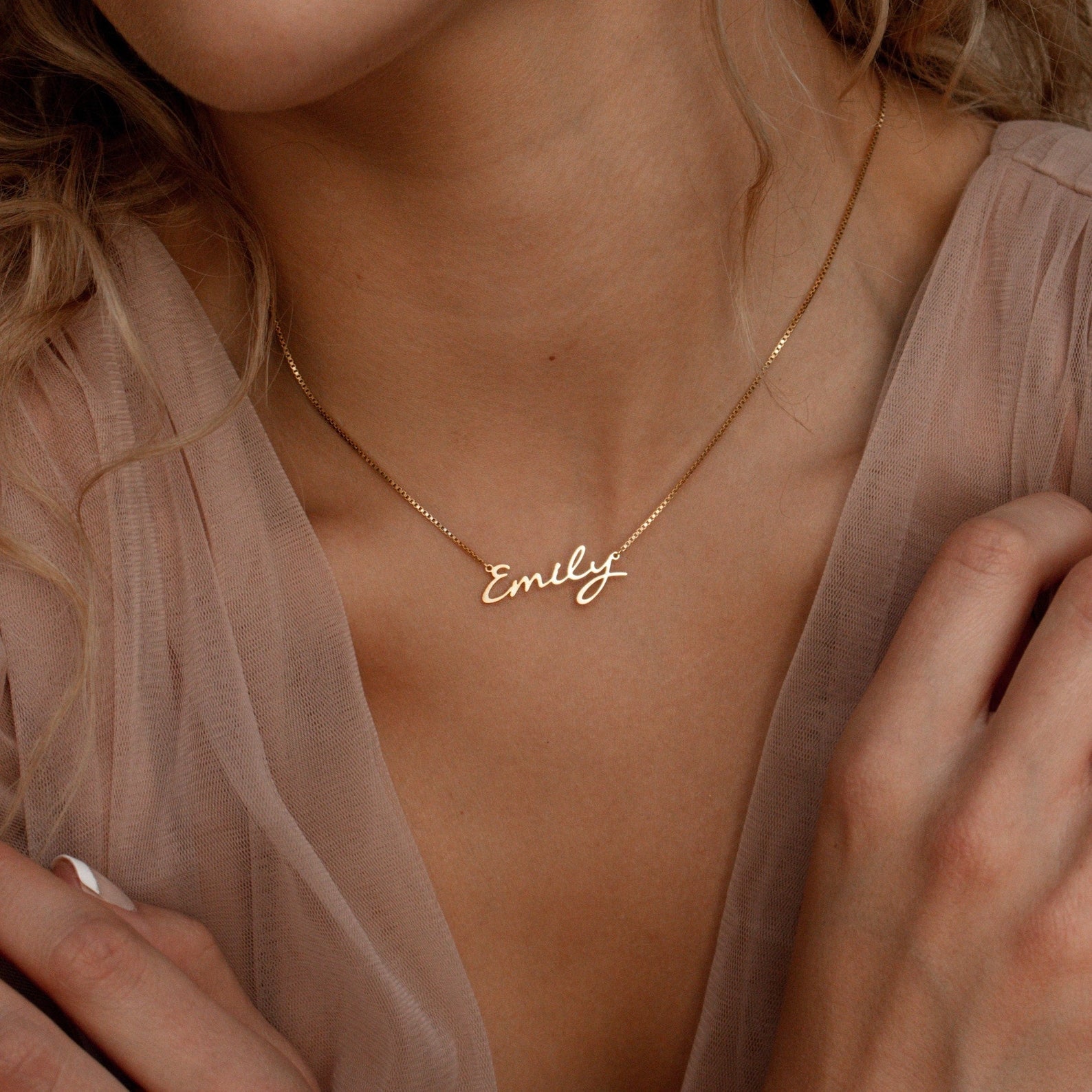 A woman wears the Callie Box Chain Name Necklace in 18K Gold, featuring "Emily" in cursive on a delicate chain.