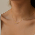 A woman wears a gold Tiny Preppy Name Necklace with "cameron" in a playful, youth-inspired font.