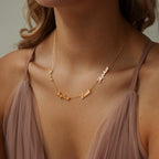 A woman wearing the Carrie Multiple Name Necklace in gold, personalized with the names Noah, Peyton, Leah, and Sophie.