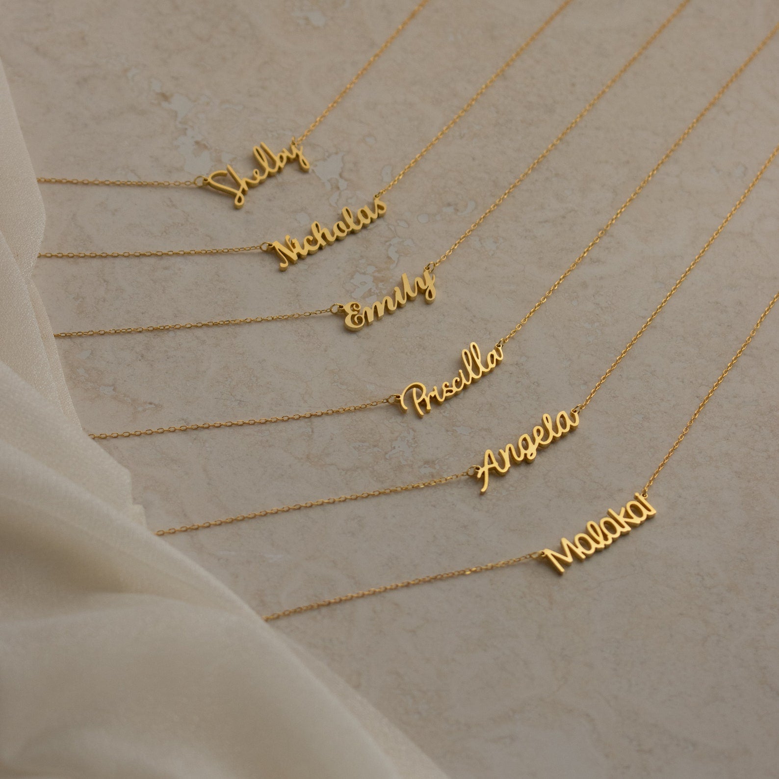 Seven Grace Name Necklaces displayed on a beige surface, each personalized with a different name in elegant cursive script.