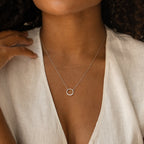 A woman wears a white blouse and the Kayla Pave Circle Necklace, highlighting her preference for minimalistic jewelry.