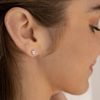 Close-up of a woman’s ear wearing Jackie Opal Studs—small, delicate studs adorned with three sparkling stones.