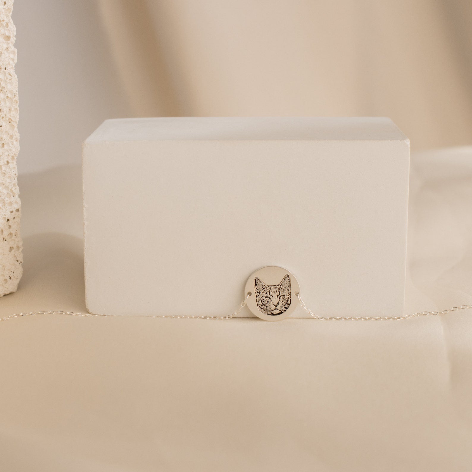 The Pet Portrait Disc Bracelet features a delicate silver round charm engraved with a cat face, displayed on a minimal beige background—an ideal memorial gift for any pet lover.