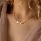 A gold Mellow Name Necklace in Curb Chain with the name Harper, crafted in a classic font, is worn by someone in a light, sheer top.