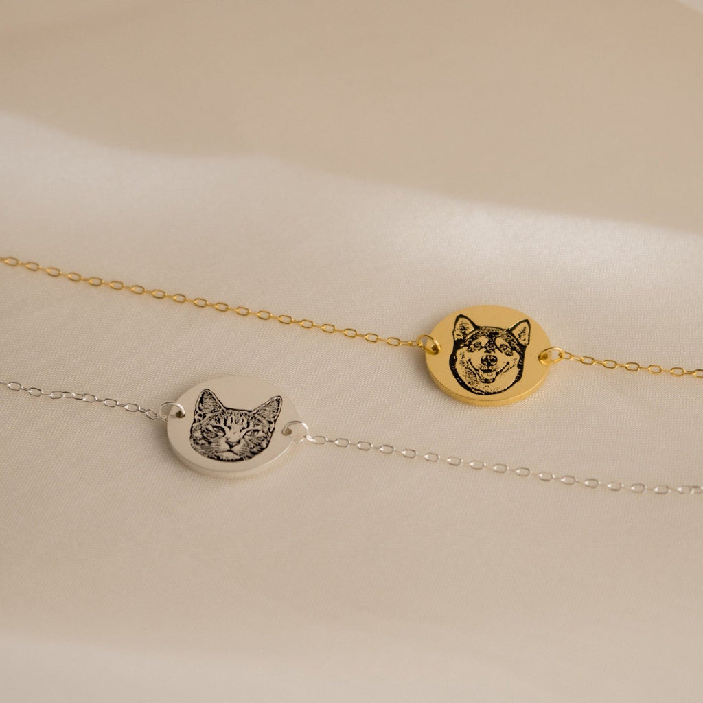 The Pet Portrait Disc Bracelet, available in gold or silver with engraved cat and dog faces on round pendants, makes a thoughtful memorial gift and is beautifully displayed on soft light fabric.