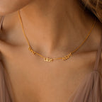 Close-up of the Preppy Multiple Name Necklace in Curb Chain, showcasing three names in a youthful font on a gold curb chain around a woman's neck.