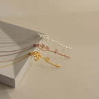 Three Flower Name Necklaces in silver, rose gold, and gold—each personalized with a name and delicate birth flowers—are displayed on a beige background.