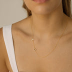 Woman in a white top wearing the Pave Sideways Initial Necklace with gold M and O letter pendants.