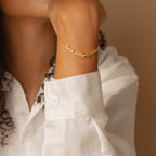A person wearing the London Multiple Name Bracelet and a white shirt, with their arm resting near their chin.
