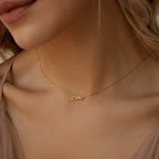 Close-up of a woman wearing the Tiny Paris Name Necklace, a delicate gold custom piece featuring a cursive pendant in an elegant Parisian font.
