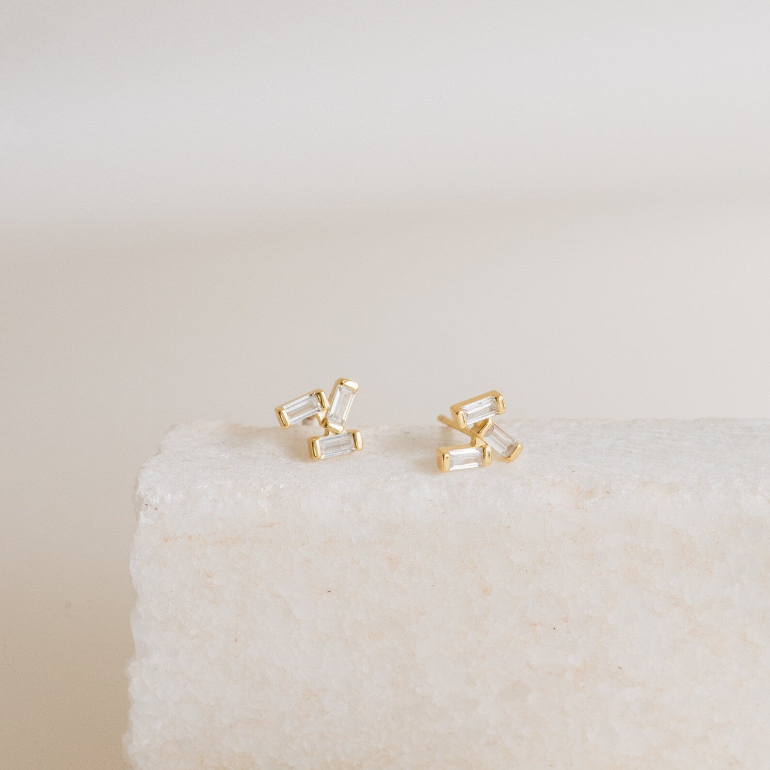 Glacier Diamond Studs showcased on a textured white stone surface with a neutral background.