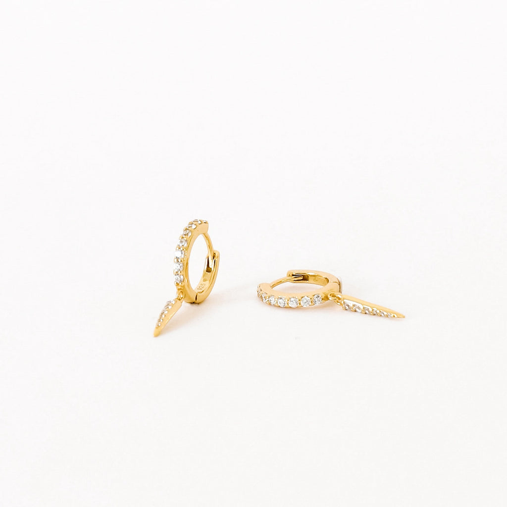 The Quinn Pave Dagger Huggies are gold diamond earrings, perfect for adding subtle elegance to any look.