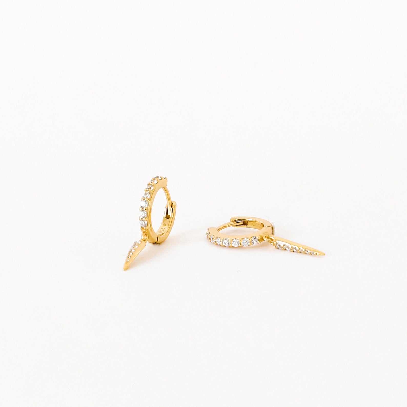 The Quinn Pave Dagger Huggies are gold diamond earrings, perfect for adding subtle elegance to any look.