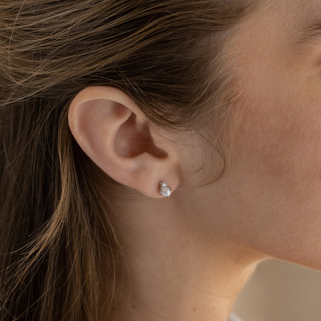 Close-up of a woman's ear wearing the Julia Pearl Studs, featuring small, round freshwater pearls.