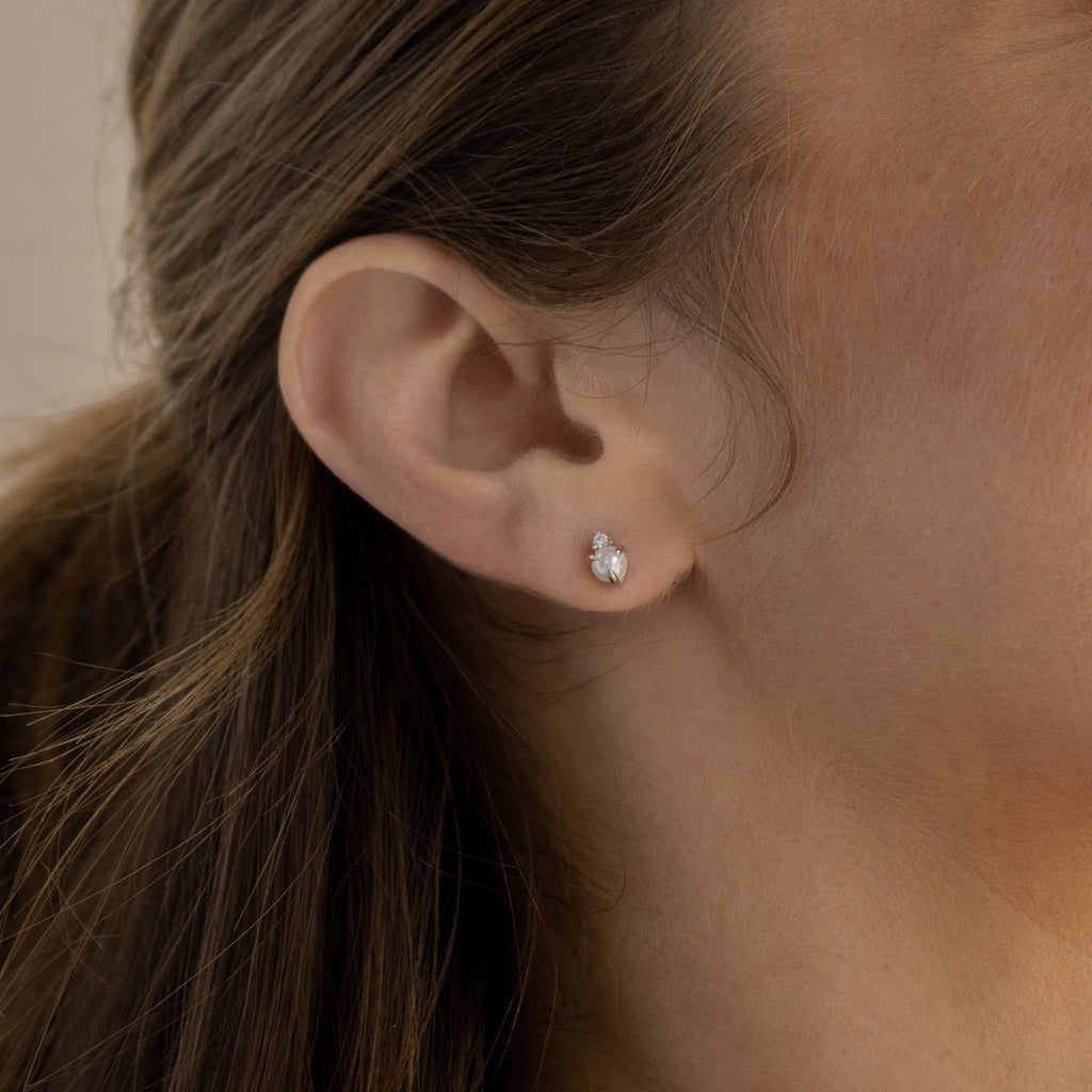 A close-up of a woman's ear adorned with the elegant Julia Pearl Studs.